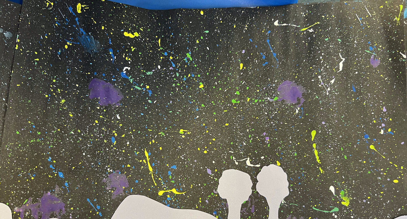 Paint-splattered night sky in yellow, blue and purple over white paper hills and trees